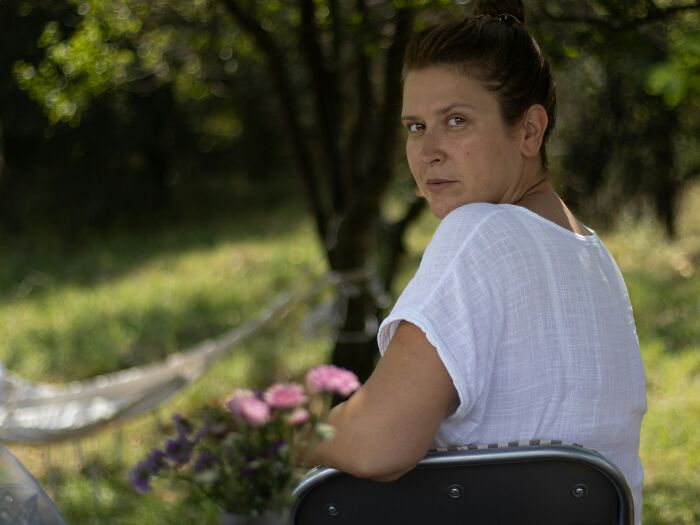 Woman sitting outdoors in a white shirt, reflecting on subtle ways misogyny has appeared in daily life.