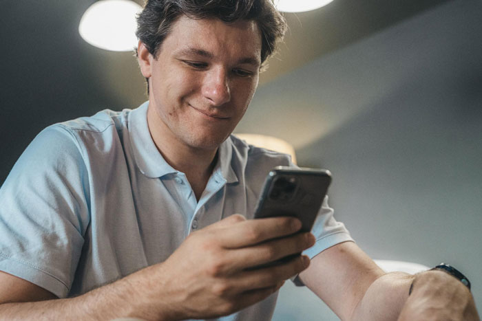 Man in a light blue shirt looking at his phone, related to pregnant wife finding out about hubby’s affair. Man in a light blue shirt looking at his phone, related to pregnant wife finding out about hubby’s affair.