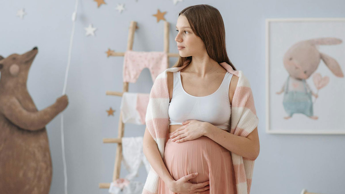 Pregnant wife standing in nursery, holding belly and looking concerned, reflecting on hubbyu2019s affair and baby name shock.