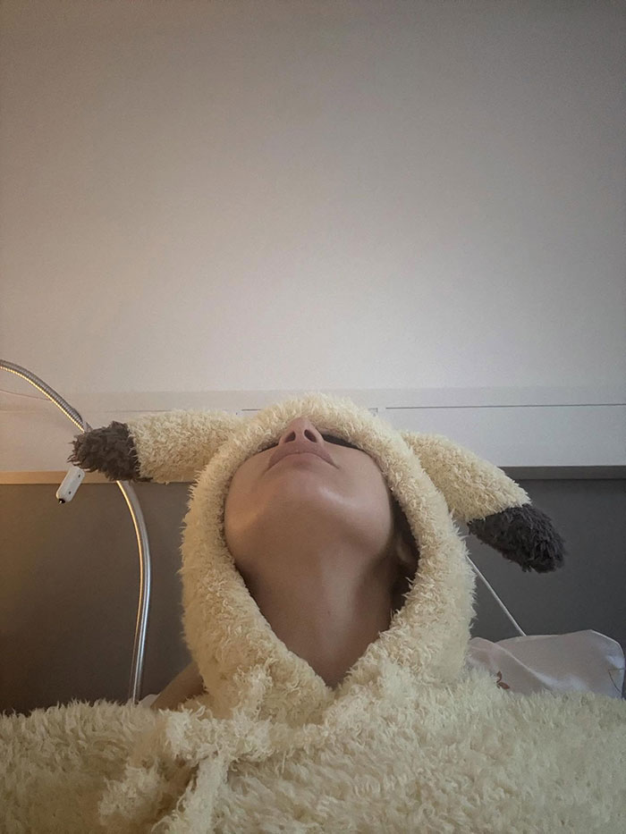 Person wearing a fluffy hooded garment with ears, lying back in a hospital setting after years of invisible suffering. Person wearing a fluffy hooded garment with ears, lying back in a hospital setting after years of invisible suffering.