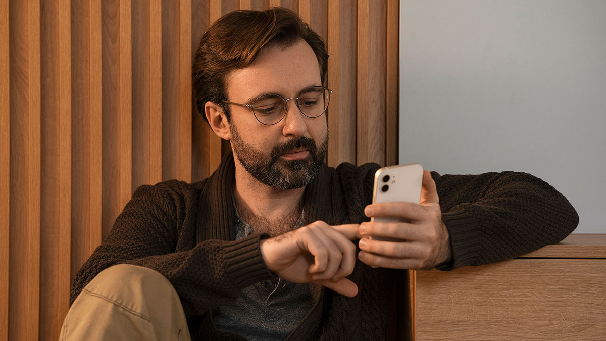 Man with glasses and beard checking smartphone, reflecting privacy concerns and strained long-term friendship disputes.