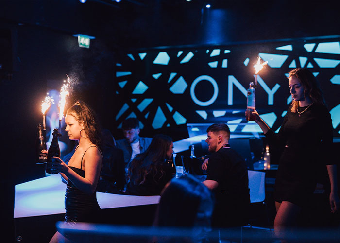 Adult star Bonnie Blue at a nightclub event with sparklers on bottles amidst a crowded party atmosphere. Adult star Bonnie Blue at a nightclub event with sparklers on bottles amidst a crowded party atmosphere.