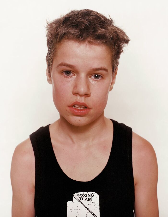 Young boxer wearing a black tank top with boxing team logo, showing determination before his first match.