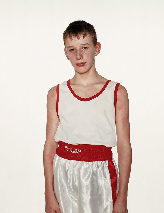Young boxer wearing white and red boxing gear posing before a match in a powerful photograph of young boxers.