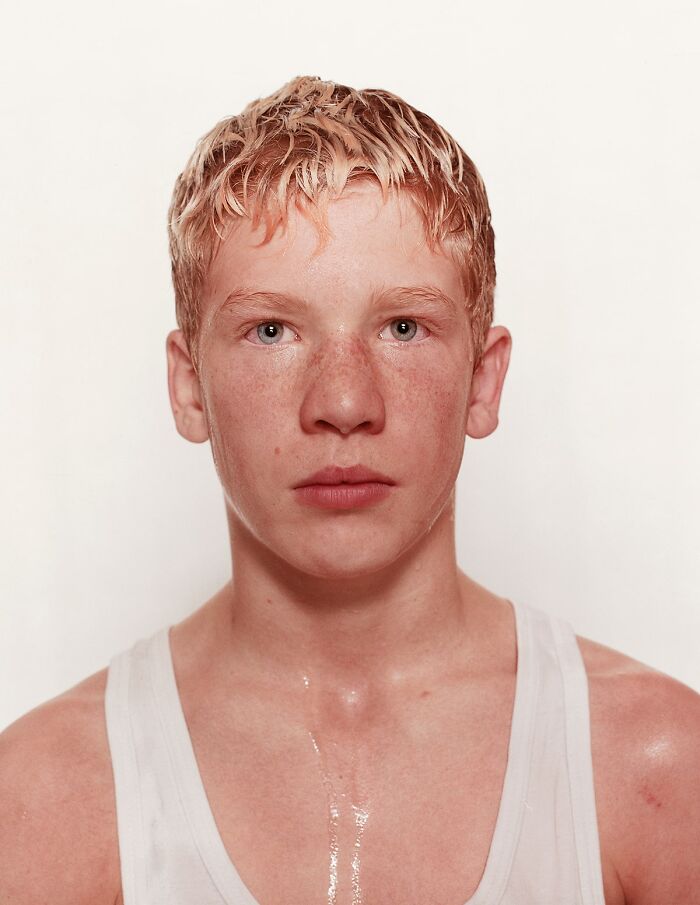 Young boxer with blonde hair and freckles wearing a white tank top, before his first match, showing determination and focus.