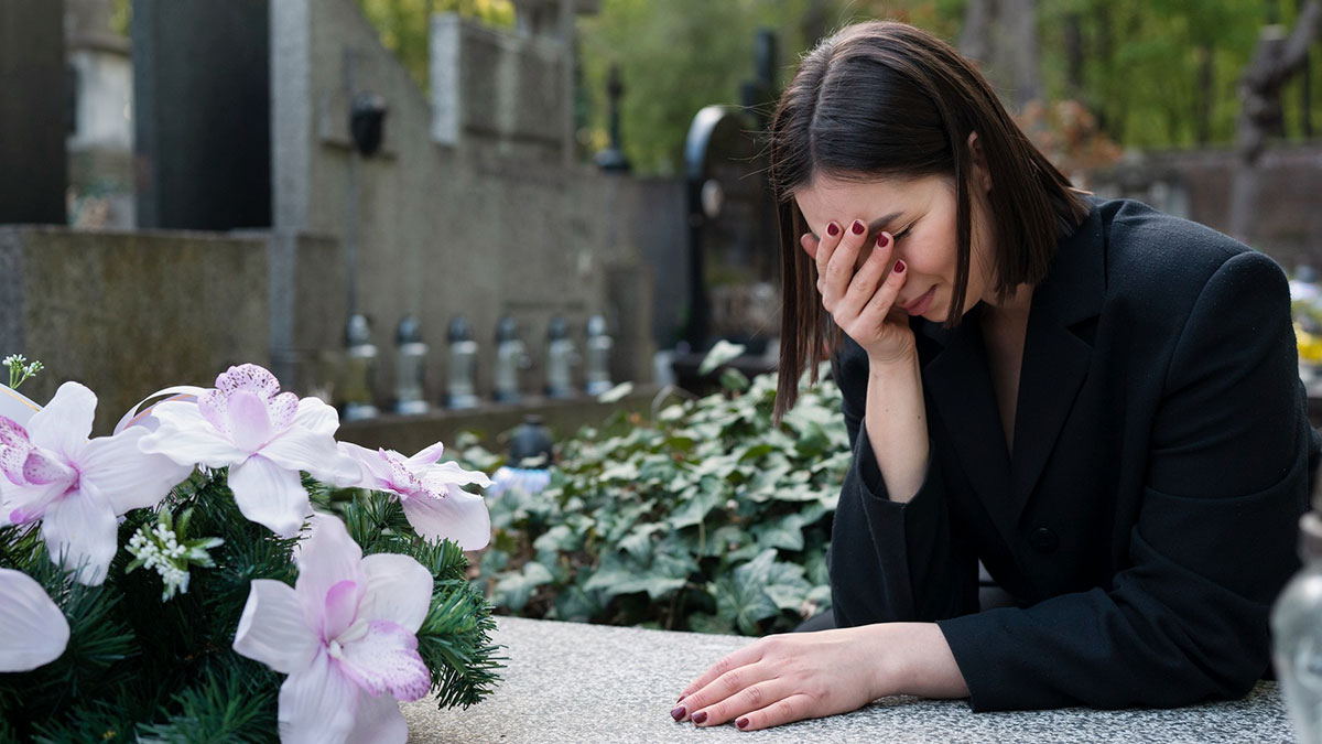 Woman grieving at a gravesite, wearing black, reflecting on condolences from a high school friend after her late boyfriend's death.