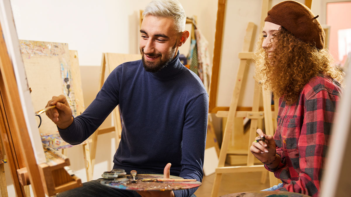 Young man and woman painting together in an art class, highlighting the shared experience of the couple.