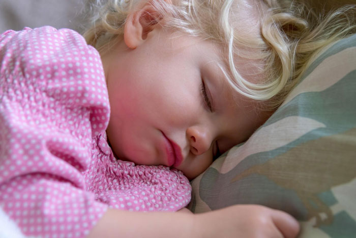 Sleeping toddler girl with blonde hair resting on pillow, representing mom caring for child amid anemia and hair fall challenges. Sleeping toddler girl with blonde hair resting on pillow, representing mom caring for child amid anemia and hair fall challenges.