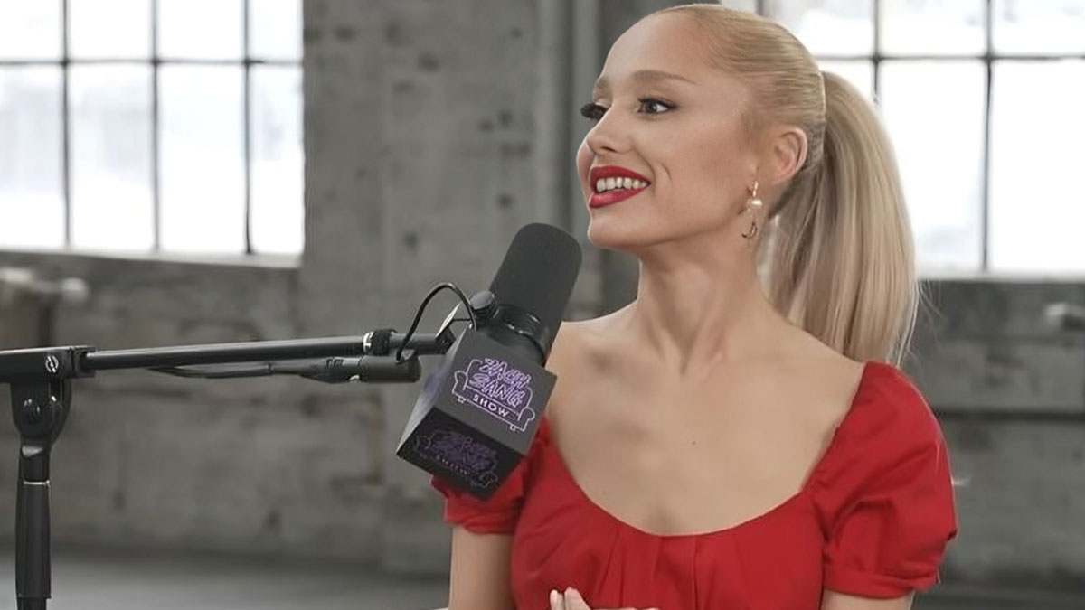 Blonde woman smiling, talking into a microphone during a celebrity interview about work and life entitlement.