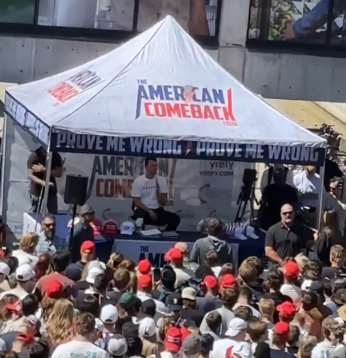 Crowd gathered at an outdoor event under a tent with American Comeback branding during witness statements on Charlie Kirk incident. Crowd gathered at an outdoor event under a tent with American Comeback branding during witness statements on Charlie Kirk incident.