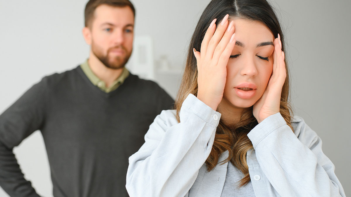 Woman looking stressed holding her head while a man stands behind her, depicting suspicion about nannying girlfriendu2019s children for free.