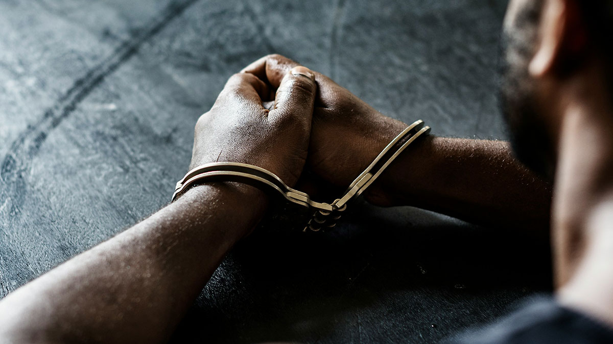 Close-up of a person with hands in handcuffs, symbolizing consequences faced by school bullies.