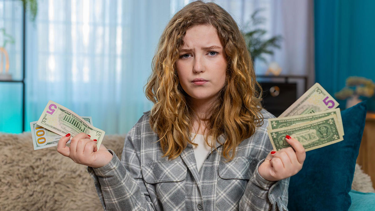 Young woman holding money with a confused expression, illustrating a childhood friend message asking for money scenario.