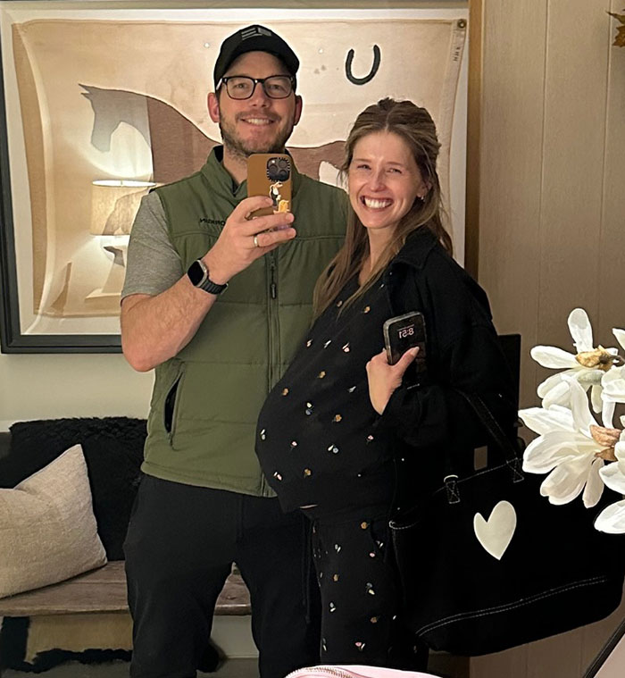 Chris Pratt smiling with a pregnant woman, casual indoor selfie, highlighting viral clip of his unique praying style. Chris Pratt smiling with a pregnant woman, casual indoor selfie, highlighting viral clip of his unique praying style.