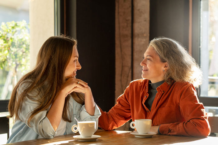 Two women having coffee in a sunlit cafe, sharing a warm moment related to Christian rapture and money dollars concepts. Two women having coffee in a sunlit cafe, sharing a warm moment related to Christian rapture and money dollars concepts.
