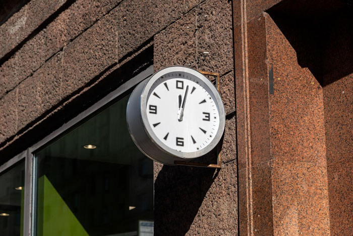 Round outdoor clock mounted on a building wall highlighting employee clock out and break time compliance story.