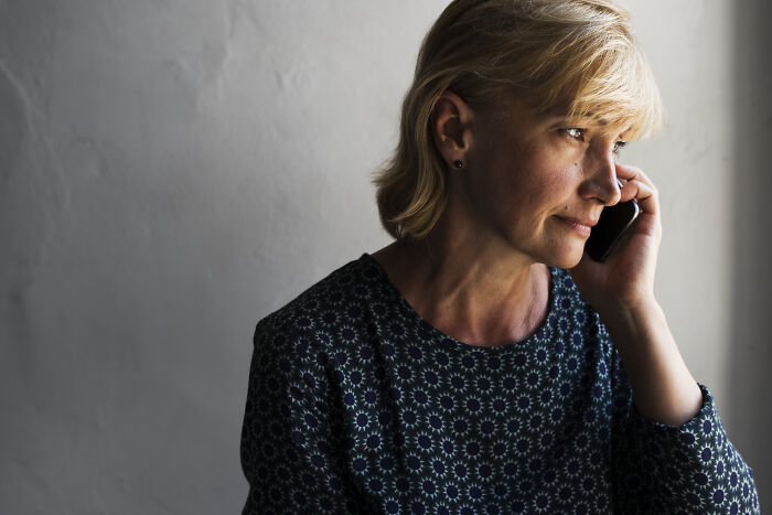 Woman with short blonde hair wearing a patterned shirt, holding a phone to her ear, sharing things people would never admit.