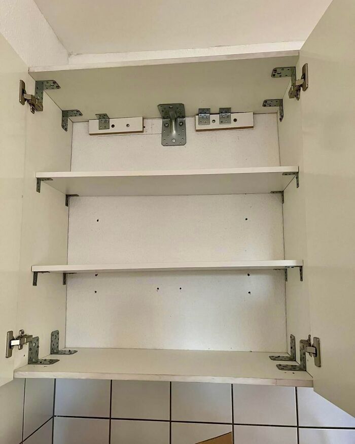 Cabinet interior with multiple unnecessary metal brackets showing construction and design flaws.