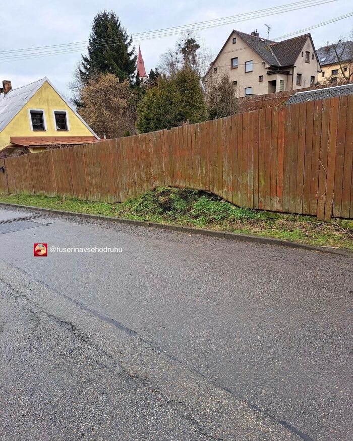 Wooden fence with a large gap at the bottom, showing a flawed construction design in a residential area.