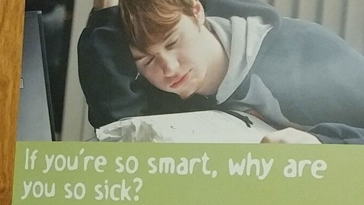 Teen boy resting head on desk looking unwell with a social media fail message about smartness and sickness.