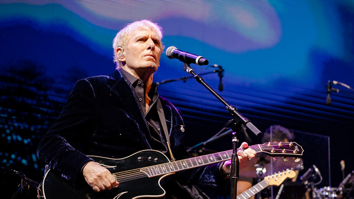 Michael Bolton performing on stage with guitar and microphone, highlighting his weird symptom before diagnosis.