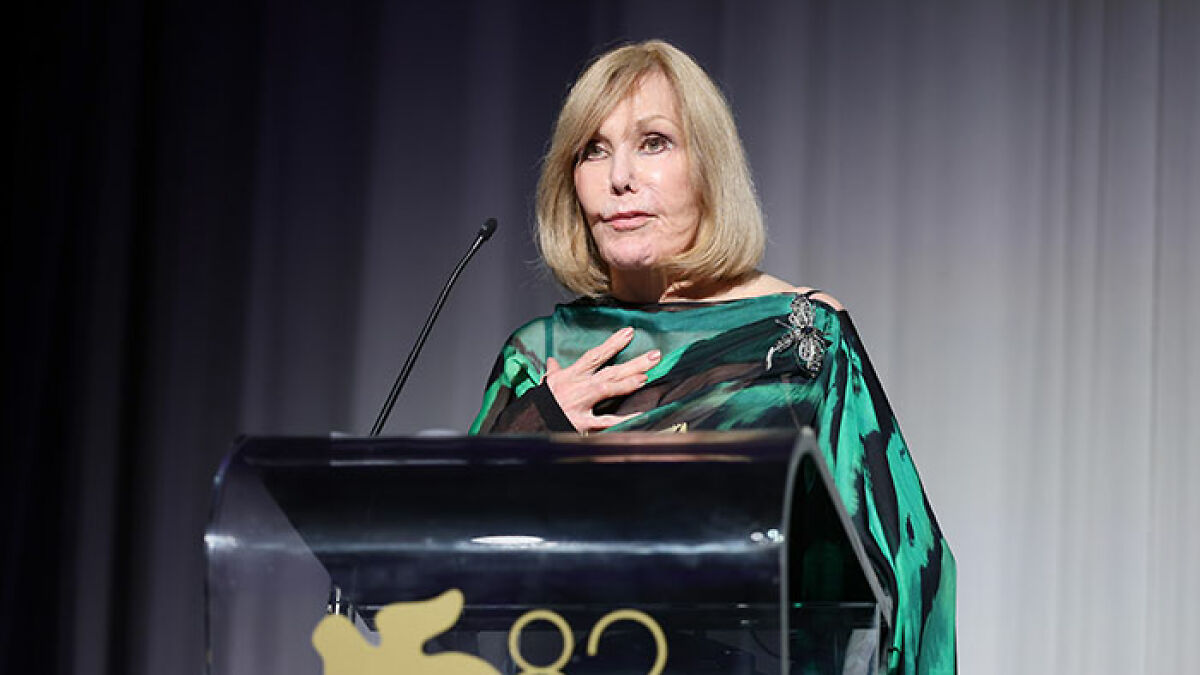 Kim Novak speaking at podium, wearing green outfit, receiving lifetime achievement award at Venice Film Festival.