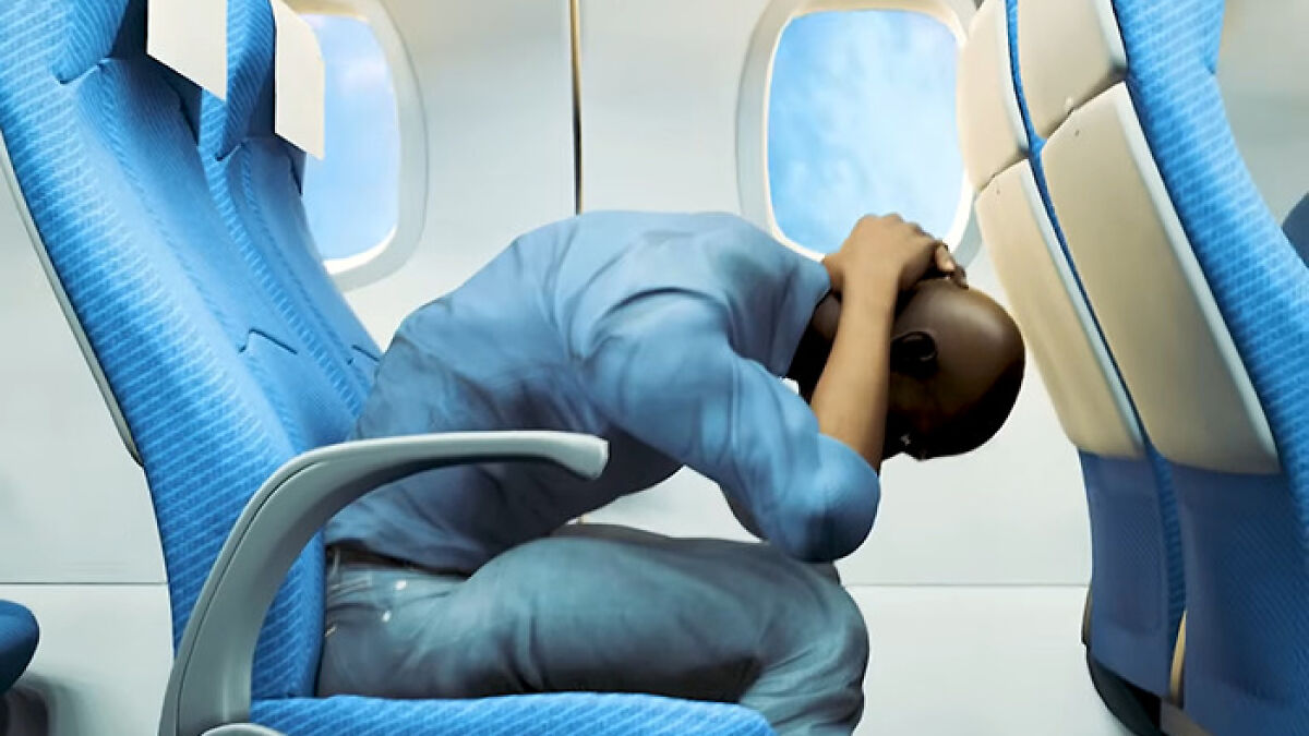 Passenger in plane crash simulation assuming emergency brace position inside airplane cabin.