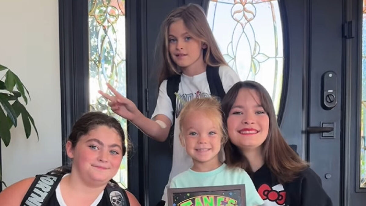 Four children smiling indoors, highlighting Dancing With The Stars pro defending her son's feminine appearance from trolls.