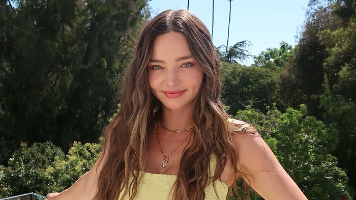 Miranda Kerr outdoors smiling with long wavy hair and wearing a yellow dress, related to Orlando Bloom breakup news.
