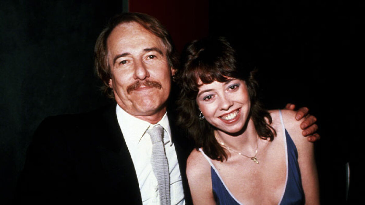 Middle-aged man and young woman smiling together, related to Mackenzie Phillips family incest allegations topic.