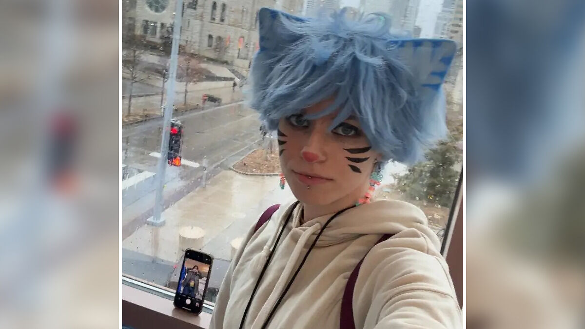 Young woman with blue furry cat ears and face paint, posing indoors near a window in Minneapolis setting.