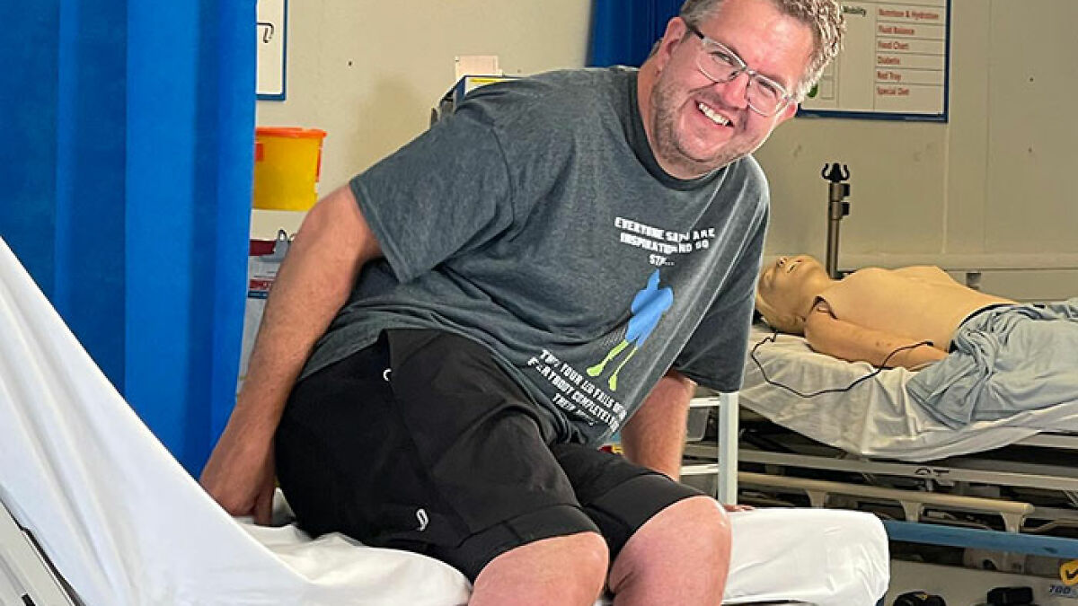 Man smiling while sitting on hospital bed in medical setting related to surgeon who had own legs amputated case