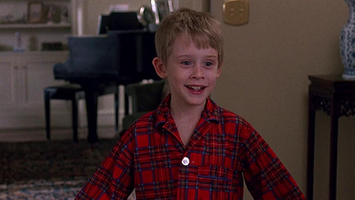 Young Macaulay Culkin smiling in red plaid pajamas in a home setting, related to John Candy and family revelations.