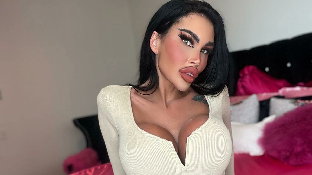 Woman known as Human Barbie with extensive body modifications posing in a white top amid plastic surgery concerns