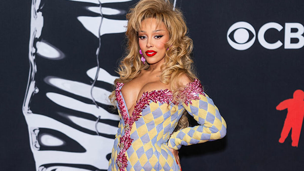Female star at the 2025 Video Music Awards in a colorful, checkered outfit with bold makeup and voluminous blonde hair.