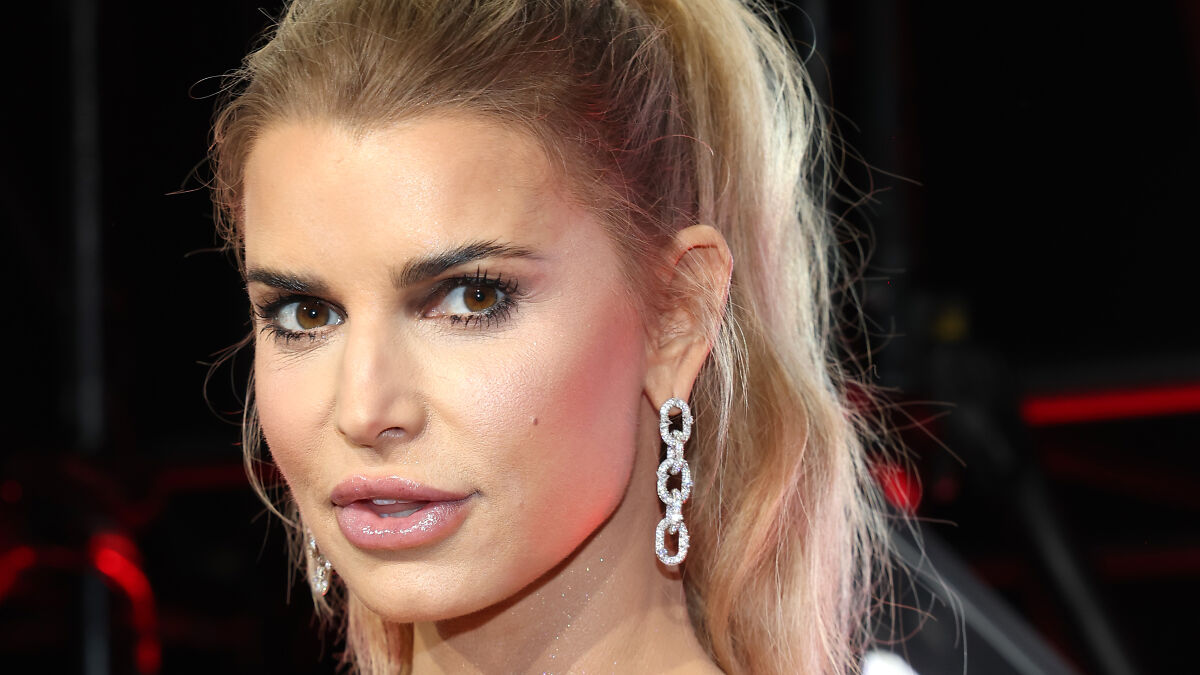 Jessica Simpson at VMAs red carpet event, wearing chain-link earrings and makeup, sparking plastic surgery rumors.