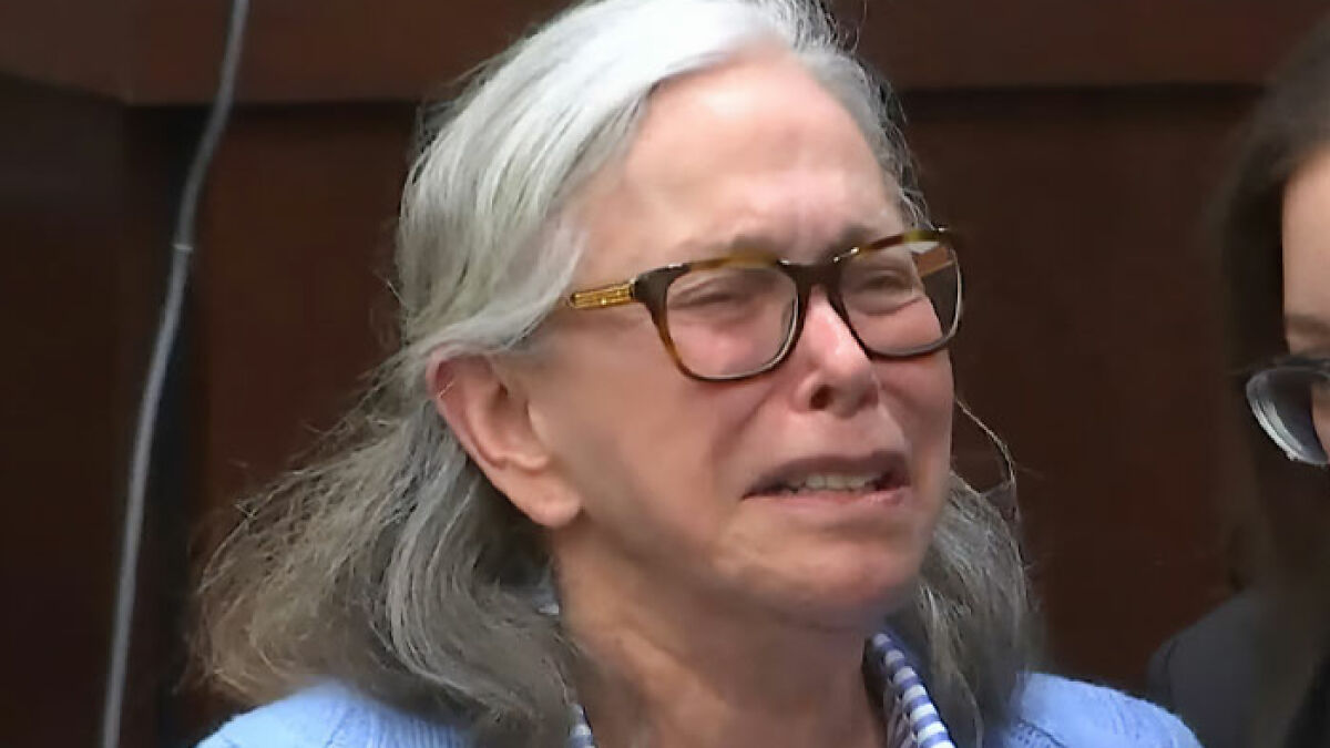 Elderly woman with gray hair and glasses crying during court hearing about a viral grandma's court meltdown.