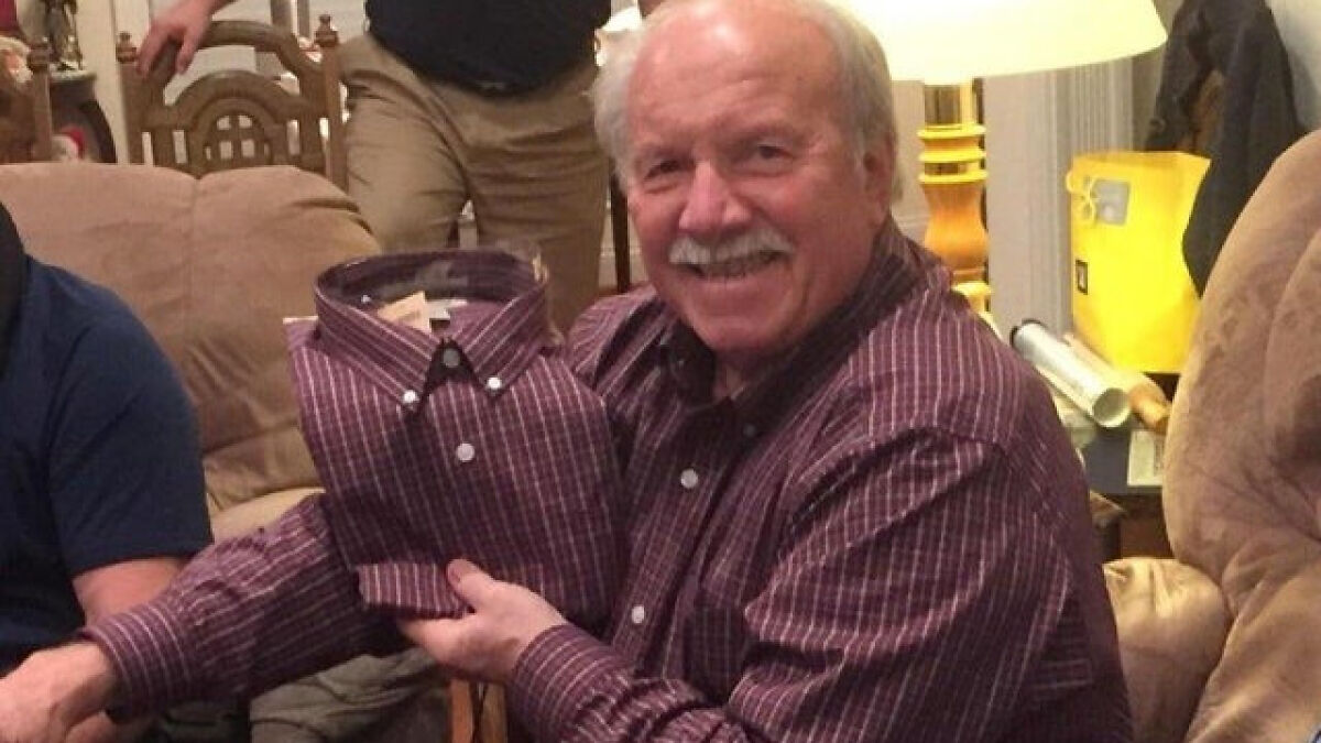 Older man smiling and holding a shirt matching his own outfit, illustrating iStove design still continues humorously.