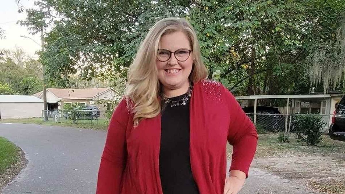 Smiling mom of five posing outdoors in red cardigan and glasses, related to mom of five missing again story.