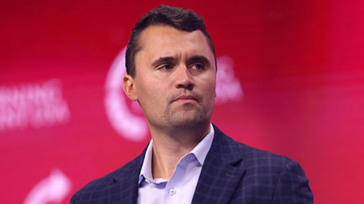 Man in a dark checked blazer and white shirt against a red background, related to FBI major update on Charlie Kirk sniper case
