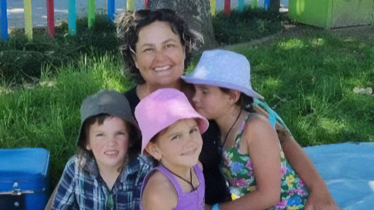 Mom of 3 missing kids smiling with children outdoors wearing hats and colorful summer clothes on grass background