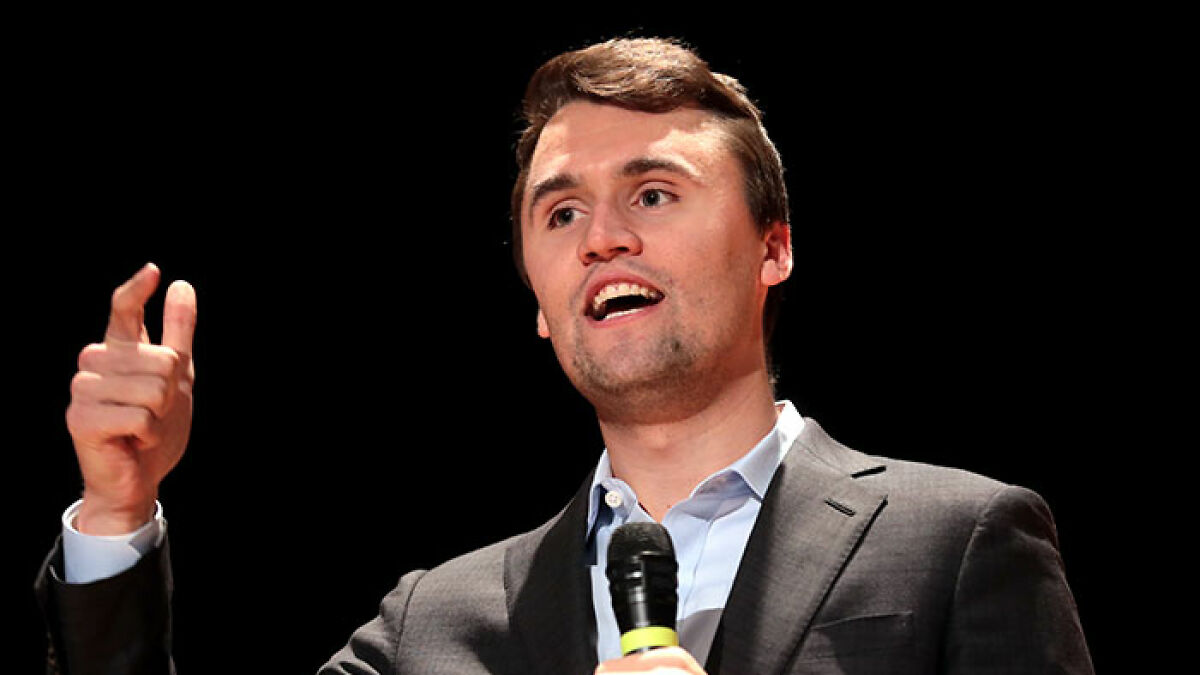 Man in suit holding a microphone speaking on stage, related to FBI evidence linking Tyler Robinson to assassination case.