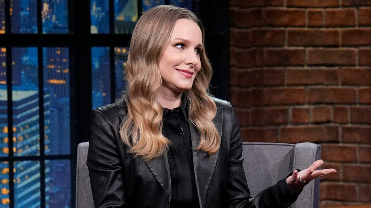 Kristen Bell smiling and gesturing while discussing the simple biohacking trick she uses to stay fit on a talk show.