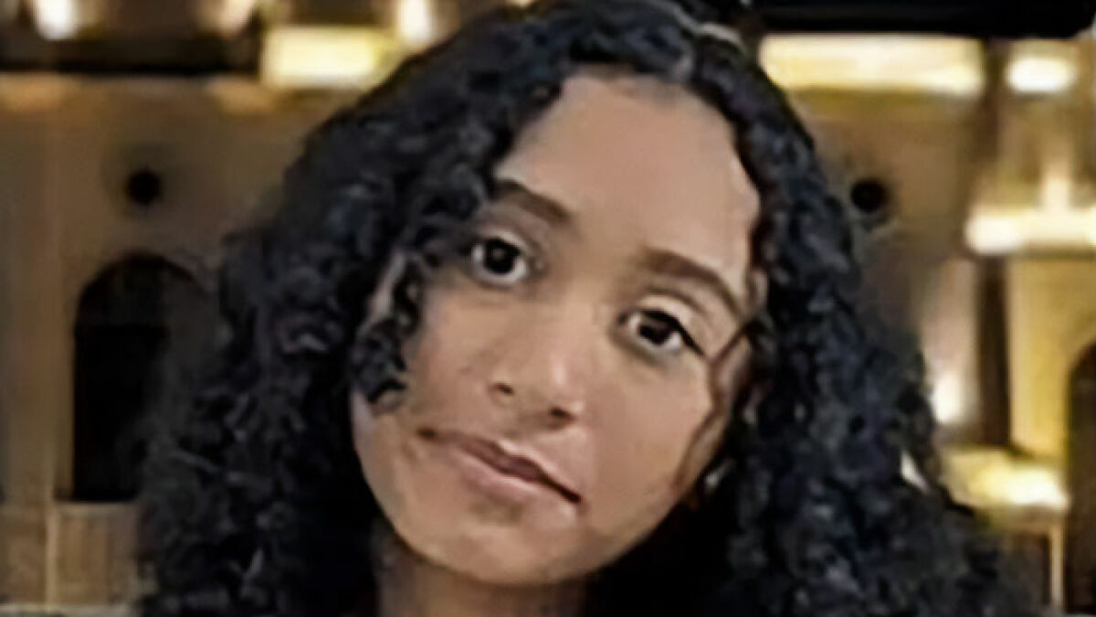 Young woman with curly hair in a dimly lit setting, related to wild findings connecting singer to missing girl case.