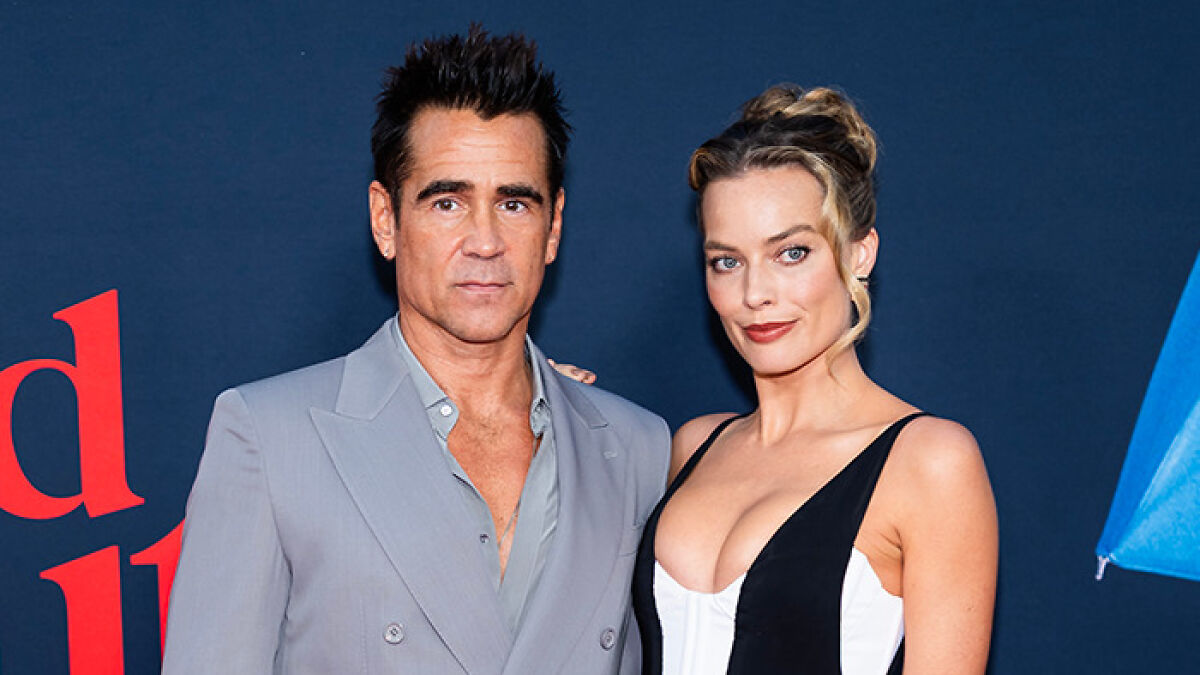 Colin Farrell and Margot Robbie posing together at an event, showcasing stylish fashion and confident expressions.