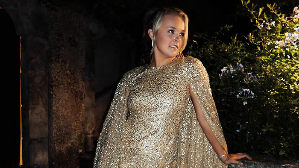 JoJo Siwa posing in a sparkling gold mini dress, captivating fans after sharing her marriage plans.