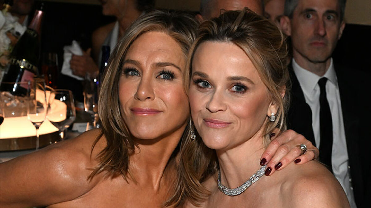 Jennifer Aniston and Reese Witherspoon posing together at a formal event, smiling and embracing.