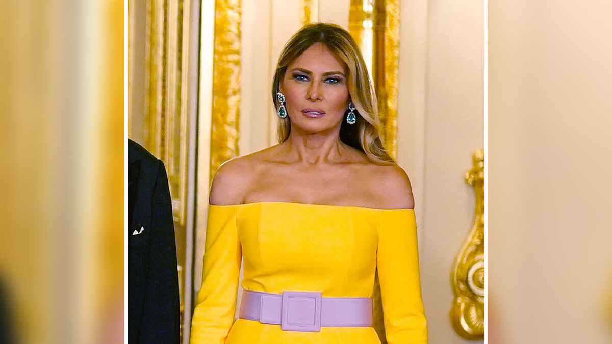 Melania Trump in a yellow off-shoulder dress and purple belt, showcasing hidden messages in wardrobe choices during UK visit.