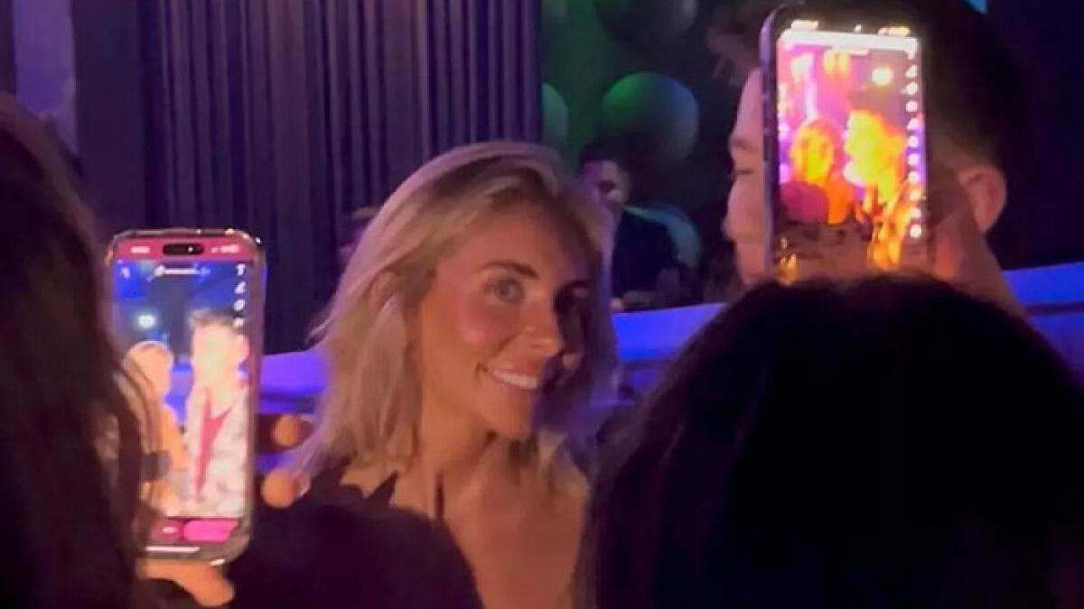 Bonnie Blue smiling at a nightclub event while being recorded on phones amid a crowd in low light surroundings.