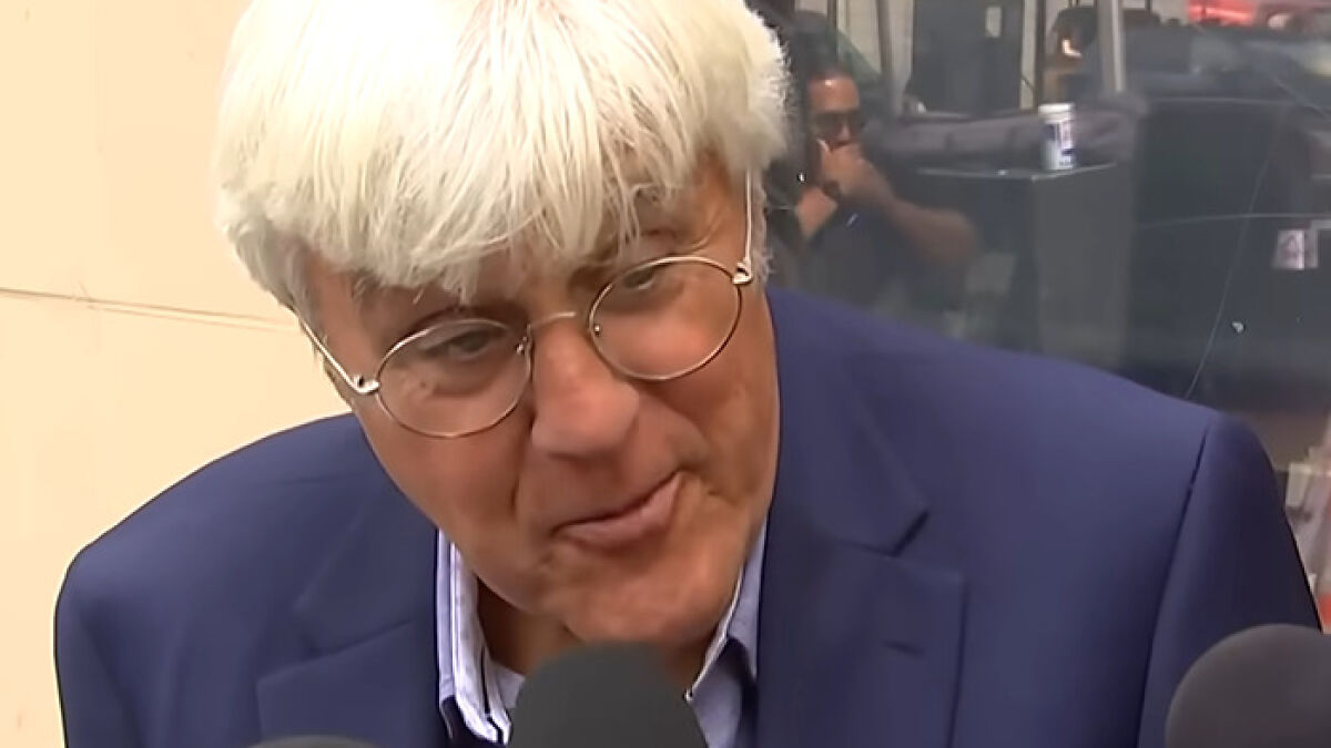 Jay Leno speaking to reporters wearing glasses and a blue blazer in a street interview about Jimmy Kimmel suspension reaction